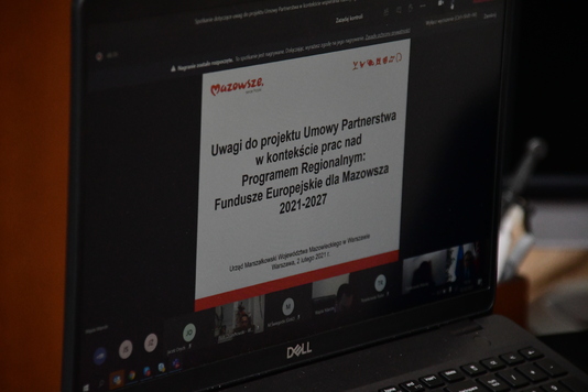 Zdjęcie otwartego laptopa, na którym wyświetla się prezentacja ze spotkania online.