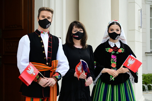 Od lewejstoją: młody mężczyzna w stroju ludowym, Janina Ewa Orzełowska, młoda kobieta w ludowym stroju