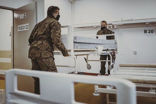 Żołnierze Wojsk Obrony Terytorialnej wnoszą łóżko szpitalne