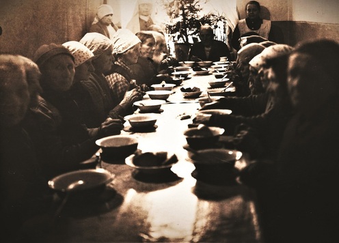 Archiwalne zdjęcie z ludźmi przy stole, w tle - siostry mariawitki