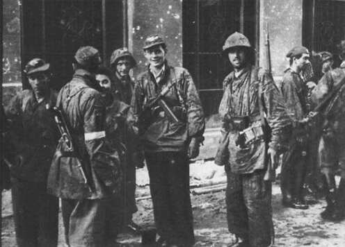 zdjęcie archiwalne z powstania, widać na nim żołnierzy, który stoją w grupie