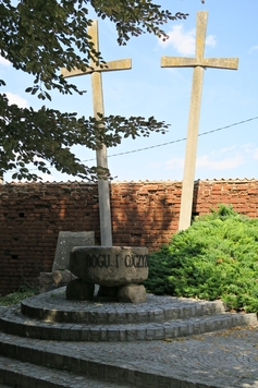 Dwa krzyże symbolizujące miecze, przed nimi kamienny ołtarz.