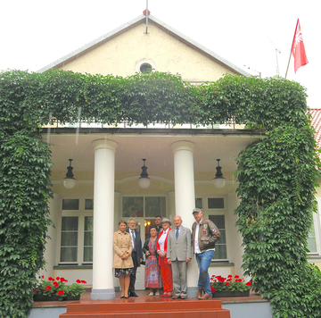 Grupa uczestników wydarzenia pozuje do zbiorowego foto przed otoczonym kolumnami wejściem do obiektu na terenie Muzeum Pozytywizmu w Gołotczyźnie.