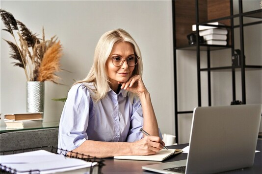 Blondynka w okularach przed ekranem laptopa