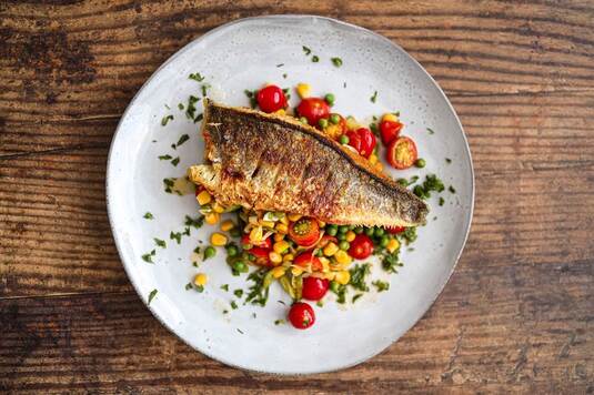 Smażona ryba z warzywami, podana na talerzu.