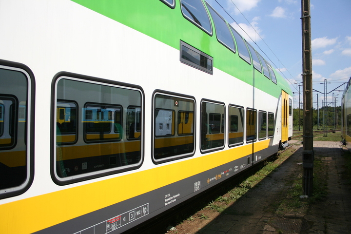 pociąg z wagonami piętrowymi w biało żółto zielonych barwach mazowieckiego przewoźnika regionalnego