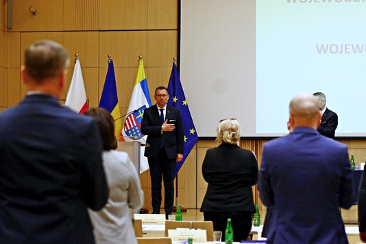 Konsul Generalny Ukrainy w Krakowie Wiaczesław Wojnarowski stoi na tle flag Unii Europejskiej, województwa świętokrzyskiego, Ukrainy i Polski.