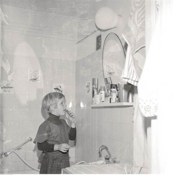 Kilkuletnie dziewczynka stoi w łazience obok półki z kosmetykami. Zdjęcie z lat osiemdziesiątych