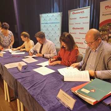 Przy stole siedzą dwie kobiety i dwóch mężczyzn, podpisują umowy