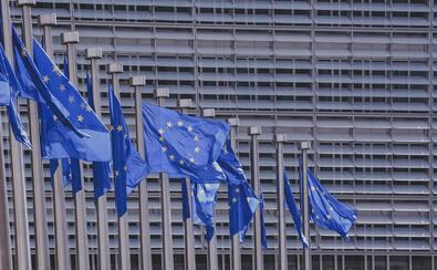 11 flag unii europejskiej powiewa na tle wieżowca