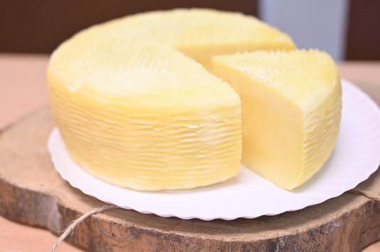 Bochen żółtego sera z wykrojonym kawałkiem sera