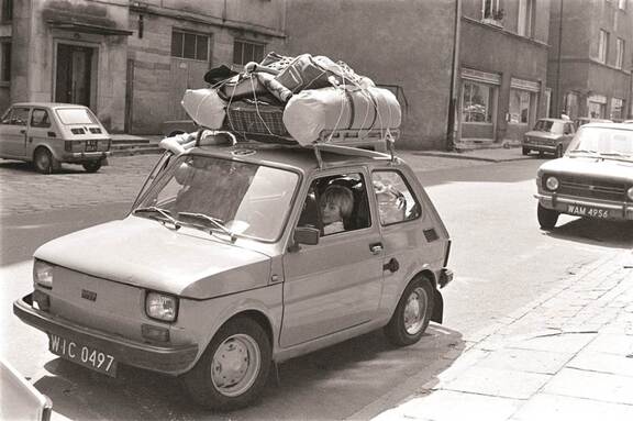 Fiat 126p z bagażnikiem dachowym pełnym walizek stoi zaparkowany przy chodniku