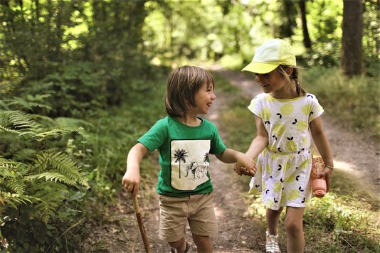 Dwoje dzieci na spacerze leśną drogą