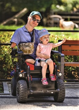 Marcin Molski na wózku z córką na kolanach