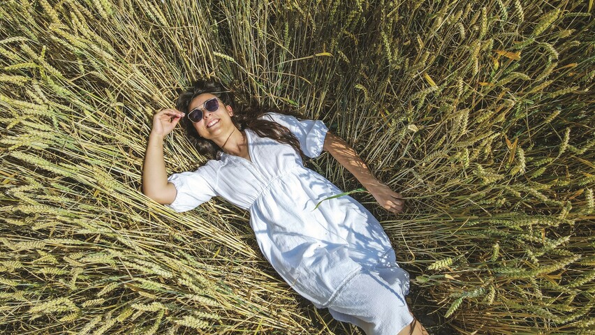 Renata Drogosz w okularach przeciwsłonecznych leży w pszenicy