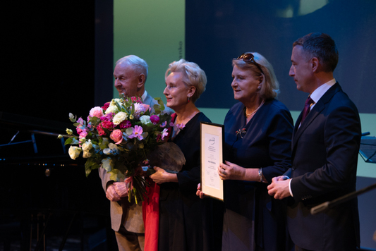 Laureatka stoi z kwiatami między Markiem Wawrzkiewiczem, Jadwigą Zakrzewską i Ludwikiem Rakowskim