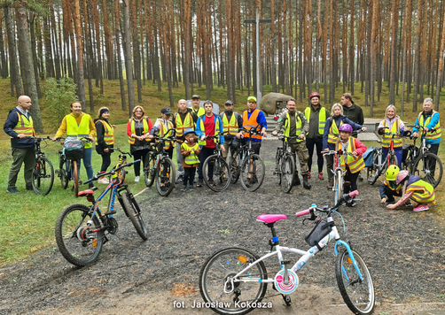 Grupa rowerzystów stoi na ścieżce rowerowej w lesie