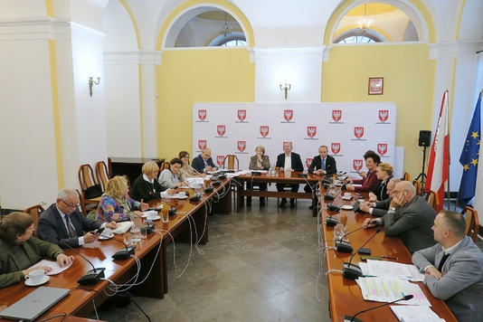 Uczestnicy posiedzenia siedzą przy stole w sali konferencyjnej Sejmiku Województwa Mazowieckiego.