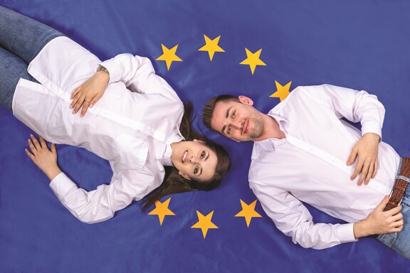 Dziewczyna i chłopak na tle flagi Unii Europejskiej