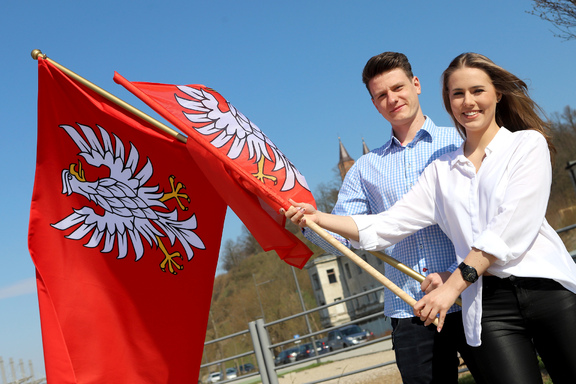 Dziewczyna i chłopak z dwiema flagami Mazowsza